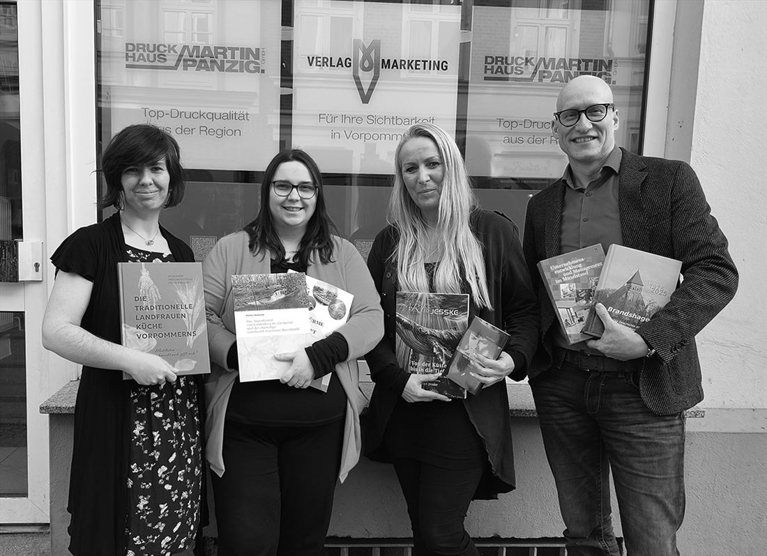 Das Team des Druckhauses Martin Panzig mit Titeln aus dem MV Verlag & Marketing vor dem Geschäft in der Fleischerstraße 4